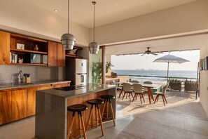 A modern kitchen with a large island, bar stools, and a view of the ocean. - 2BR Beachfront Villa + Pool, Style & Sea Views (Zihuatanejo)