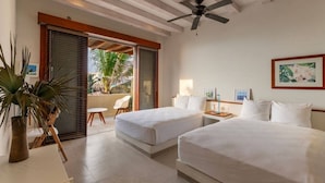 A hotel room with two beds, a ceiling fan, a small table with a lamp, and a view of the outdoors. - 2BR Beachfront Villa + Pool, Style & Sea Views (Zihuatanejo)