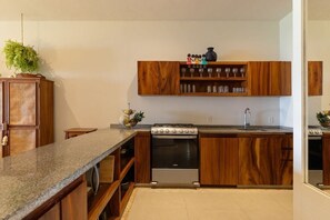 A kitchen with wooden cabinets, a granite countertop, a stove, and a hanging plant.