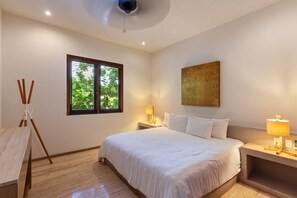 Quarto de hotel com cama, abajures, janela com persianas e ventilador de teto.