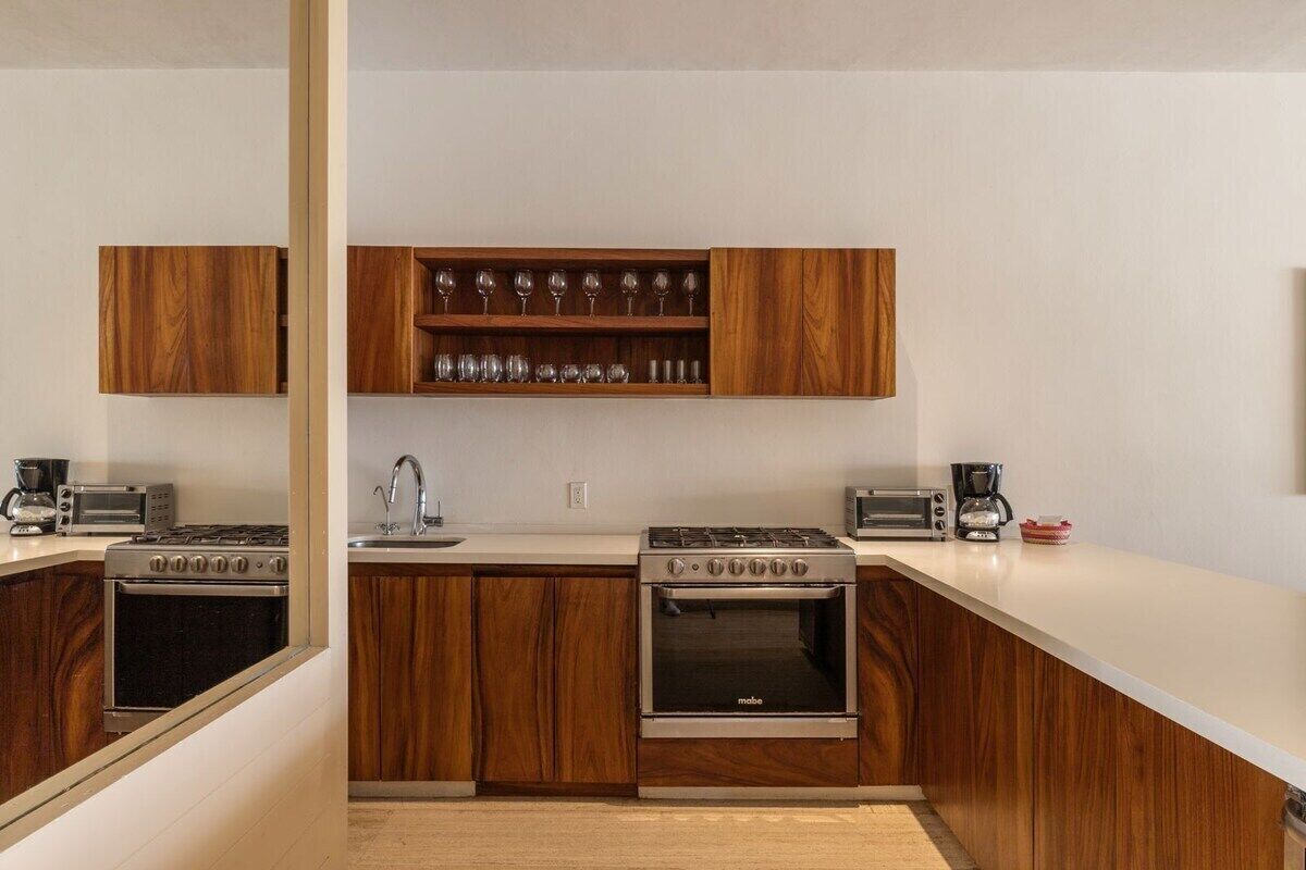 Una cucina moderna con mobili in legno, una dispensa per vini, un piano cottura a gas, un forno e una macchina da caffè.