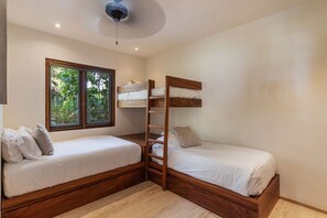A room with two bunk beds, a window with blinds, and a ceiling fan.