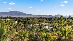 A landscape with palm trees, a swimming pool, and distant mountains. - Elegant 2BR Villa I Ocean View + Artful Style (Zihuatanejo)