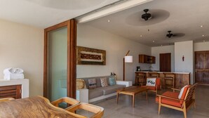 A spacious living area with a wooden dining table, a sofa, and a kitchen in the background.