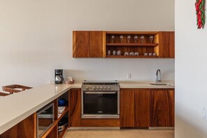 Una cocina moderna con armarios de madera, horno empotrado y una encimera con cafetera.