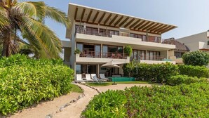 Un edificio de dos pisos con un balcón, una piscina y un jardín bien cuidado.
