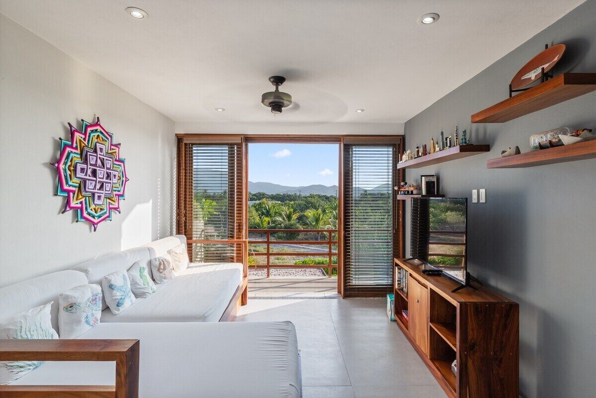 A modern living room with a sofa, television, and wooden shelves.