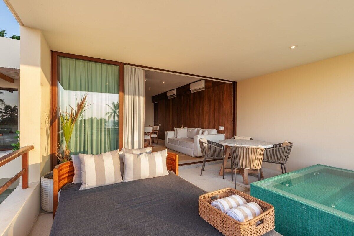 A modern bedroom with a large bed, a dining area, and a hot tub.