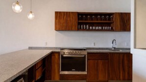 A kitchen with wooden cabinets, a built-in oven, and pendant lighting. - Stylish 3BR Villa I Pool & Sunset Views (Zihuatanejo)