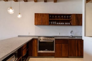 A kitchen with wooden cabinets, a built-in oven, and pendant lighting. - Stylish 3BR Villa I Pool & Sunset Views (Zihuatanejo)