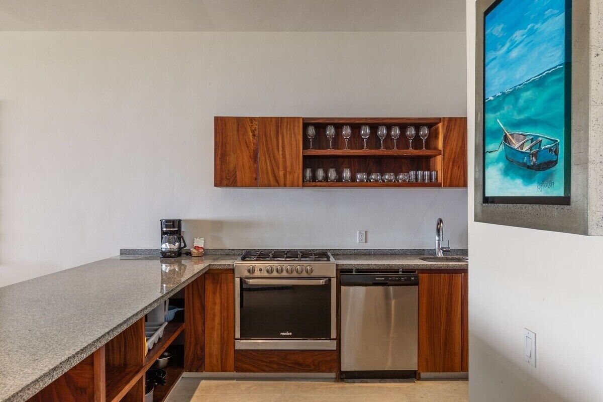 A modern kitchen with wooden cabinets, a built-in wine rack, a stove, and a dishwasher.