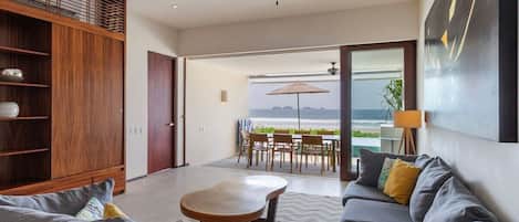 Un salon moderne avec un canapé, une table basse et une vue sur l’océan grâce à de grandes fenêtres.