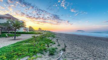 A beach with a clear sky, a sandy shore, and a building with a sloped roof.
