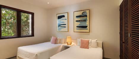 A hotel room with two beds, a window with blinds, and artwork on the wall.