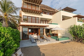 A multi-story building with a balcony, outdoor seating, and a pool area.