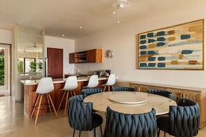 A modern kitchen with a central island, bar seating, and a dining area with round table and chairs.