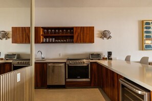 A modern kitchen with wooden cabinets, a built-in wine rack, stainless steel appliances, and a large island.
