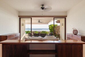 A modern room with a wooden desk, a ceiling fan, and a view of the ocean.