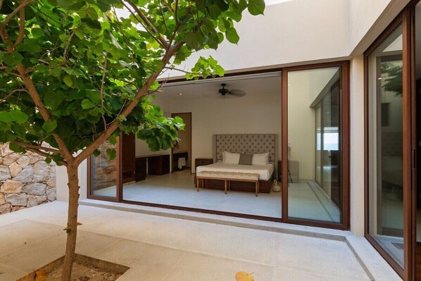 A bedroom with a bed, a ceiling fan, and a large window.