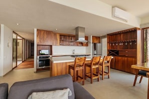 A modern kitchen with wooden cabinets, a central island with chairs, and a dining area.