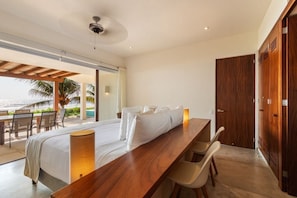 A hotel room with a bed, a wooden desk, and a view of the ocean.