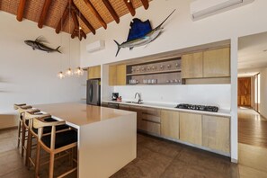 A modern kitchen with a central island, wooden bar stools, and a ceiling with woven beams. - 3BR Ocean Penthouse I Private Pool + Sunset Deck (Zihuatanejo)