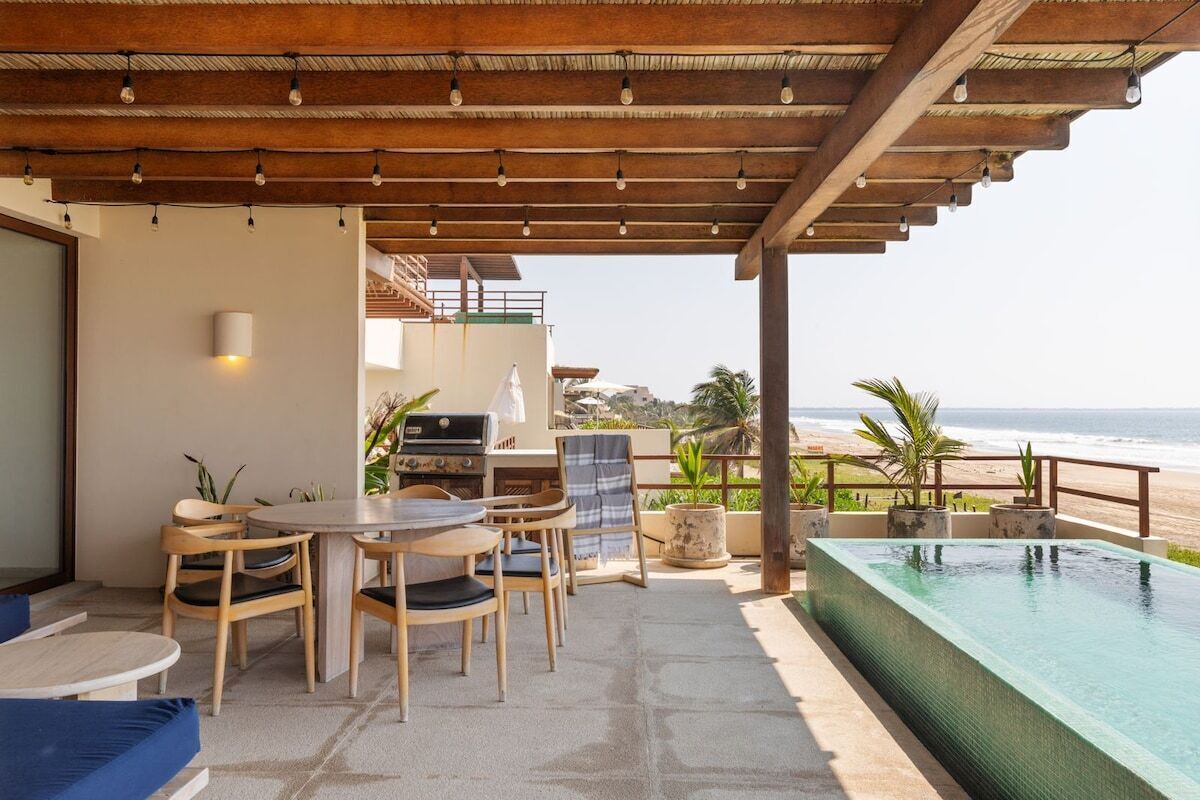A covered outdoor area with a pool, seating, and a grill.