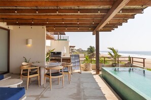 A covered outdoor area with a pool, seating, and a grill.