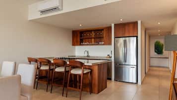 Une cuisine moderne dotée d’un îlot central, d’appareils électroménagers en acier inoxydable et de meubles de rangement en bois.