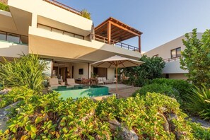 A modern two-story building with a swimming pool, outdoor seating, and lush greenery. - 3BR Beachfront Villa • Pool, Terrace • Sleeps 6 (Zihuatanejo)