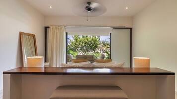 Une salle de bain moderne avec un grand miroir, un banc et une vue sur un espace extérieur tropical.
