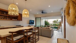 A modern kitchen with a dining area, a television, and a view to the outdoors.
