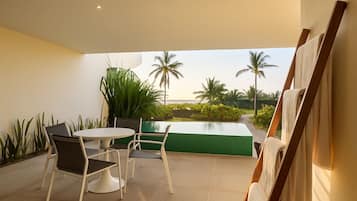 Un espace extérieur moderne aménagé avec une table et des chaises, un mur végétal et une vue sur des palmiers et une piscine.