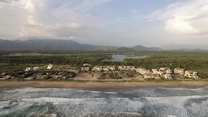 A coastal resort with beachfront villas, a beach, and a mountainous backdrop.