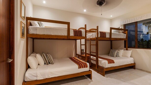 A room with bunk beds, a ceiling fan, and a window with a view.