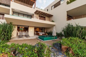 Un immeuble moderne à plusieurs étages, doté d’une terrasse sur le toit, d’une piscine et d’un jardin aménagé.