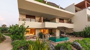 Un edificio a più piani con piscina, area salotto esterna e giardino.