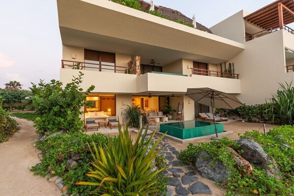 A multi-story building with a pool, outdoor seating, and a garden area.