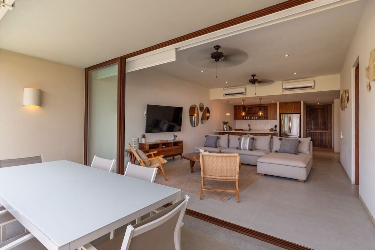 A modern living room with a dining table, sofa, and TV.