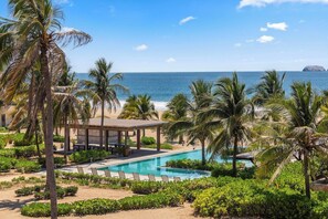 A resort with a pool, palm trees, and a view of the ocean. - Family-Friendly 2BR I Pool + Beach Views (Zihuatanejo)