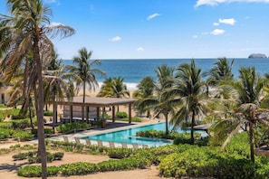 A resort with a pool, palm trees, and a view of the ocean.
