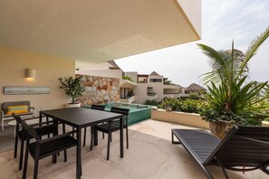An outdoor patio with a dining table and chairs, a lounge chair, a small pool, and a stone wall. - Romantic 1BR Villa • Private Pool + Outdoor Shower (Zihuatanejo)