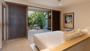 Une chambre moderne avec un grand lit, un banc en bois et une vue sur un jardin extérieur.