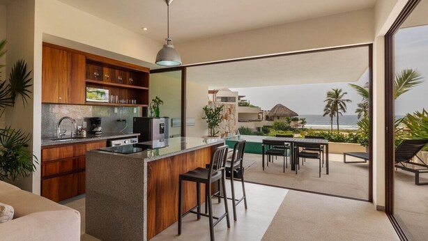 Une cuisine moderne dotée d’un bar, d’un espace repas et offrant une vue sur l’océan.