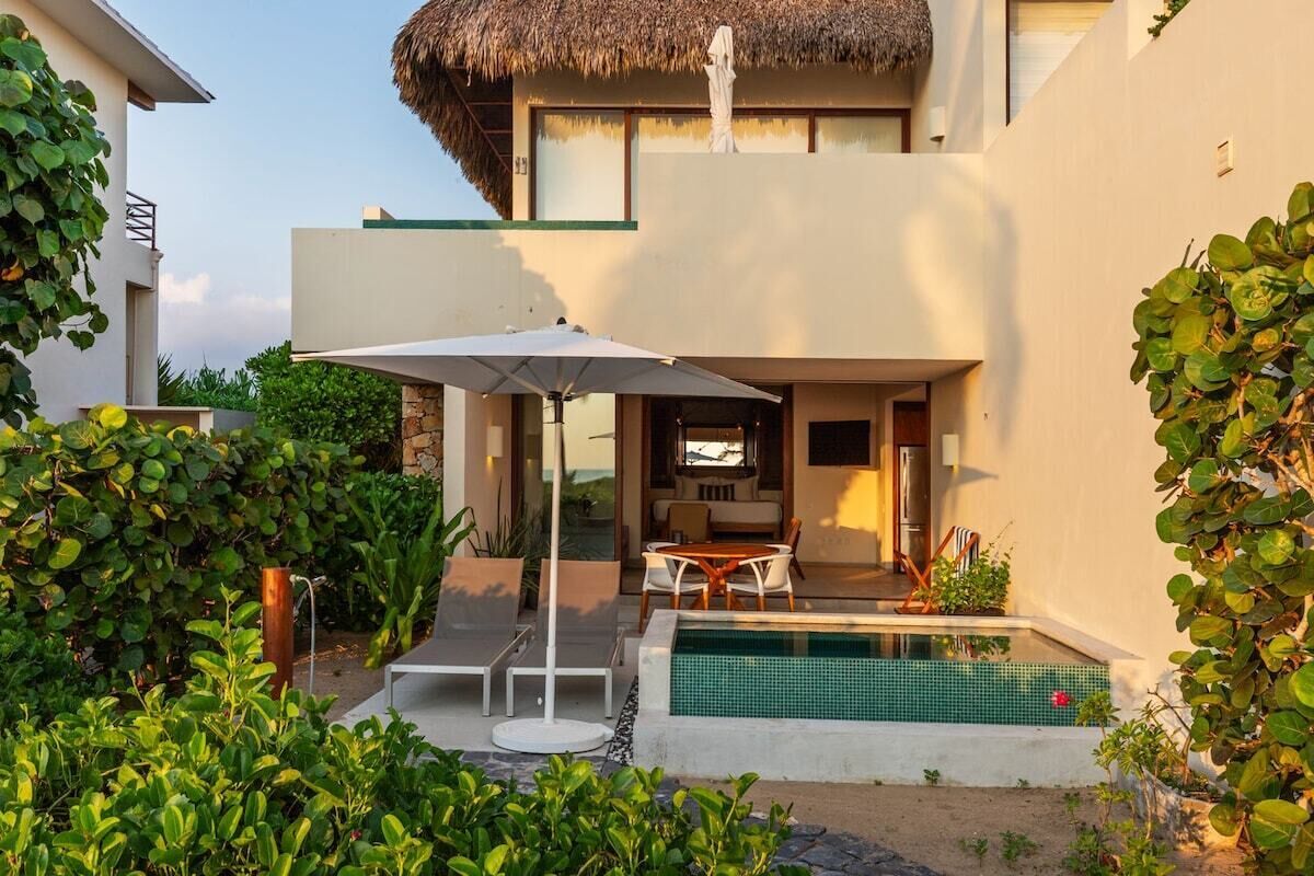 A modern house with a swimming pool, outdoor seating, and a thatched roof.