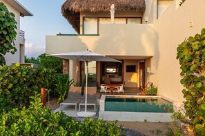 Una casa moderna con piscina, mobiliario exterior y techo de paja.