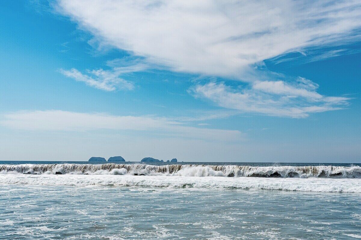 A coastal view with waves and distant landforms.