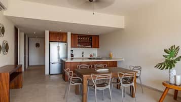 A stylish open-concept kitchen and dining area featuring wooden accents, bar seating, and top-of-the-line appliances.