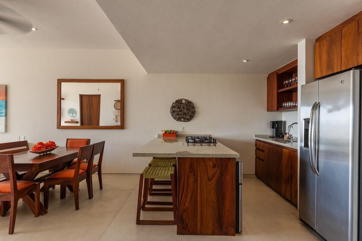 Une cuisine moderne dotée d’un îlot central, de meubles en bois et d’un réfrigérateur en acier inoxydable.