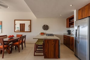 Een moderne keuken met een centraal kookeiland, houten kastjes en een roestvrijstalen koelkast.